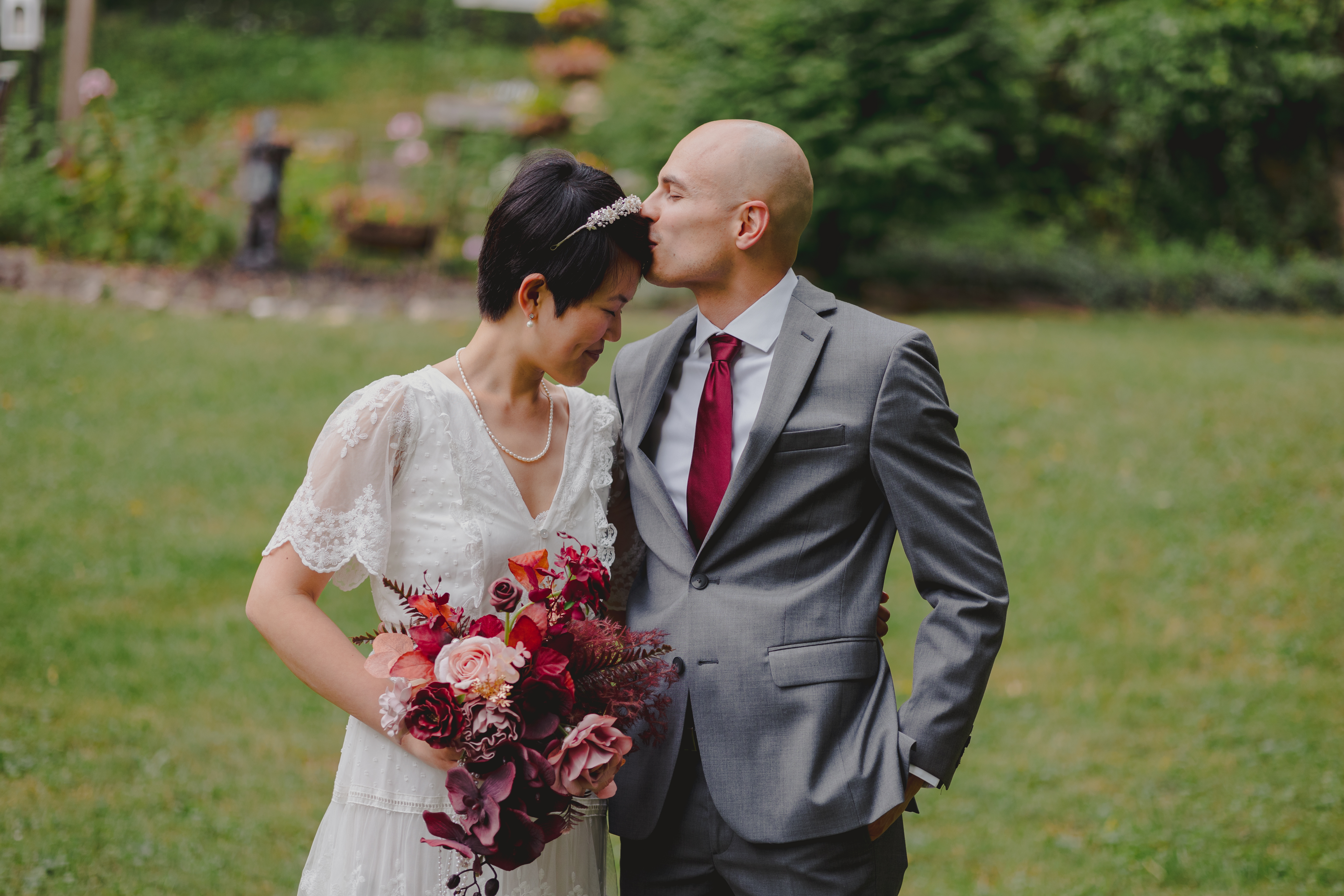 A groom giving a bride a forehead kiss.