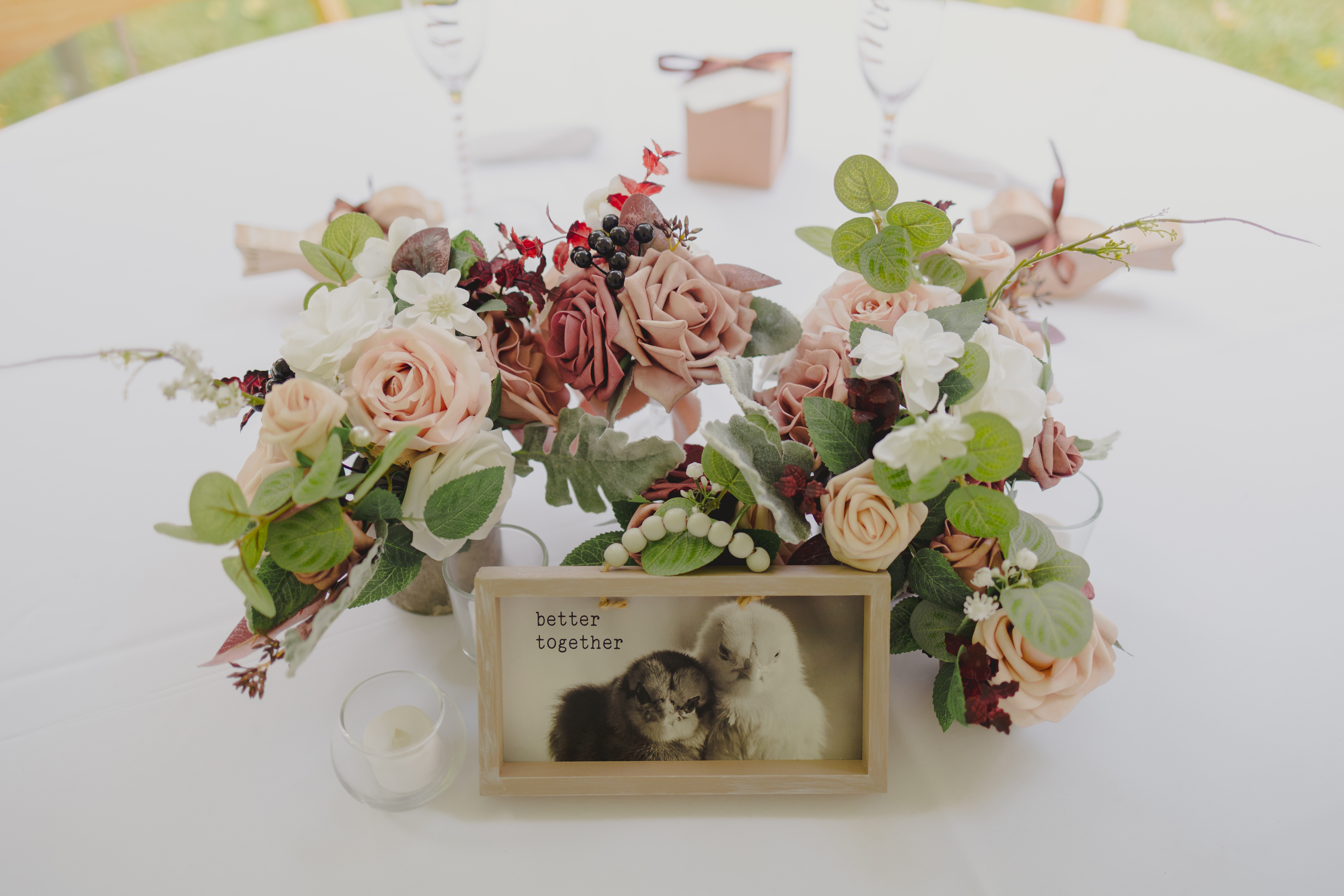 Simple decoration for a head table at a wedding. The table has flowers and a sign with grumpy chickens.