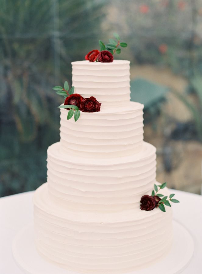 A photo of a white wedding cake with red flowers