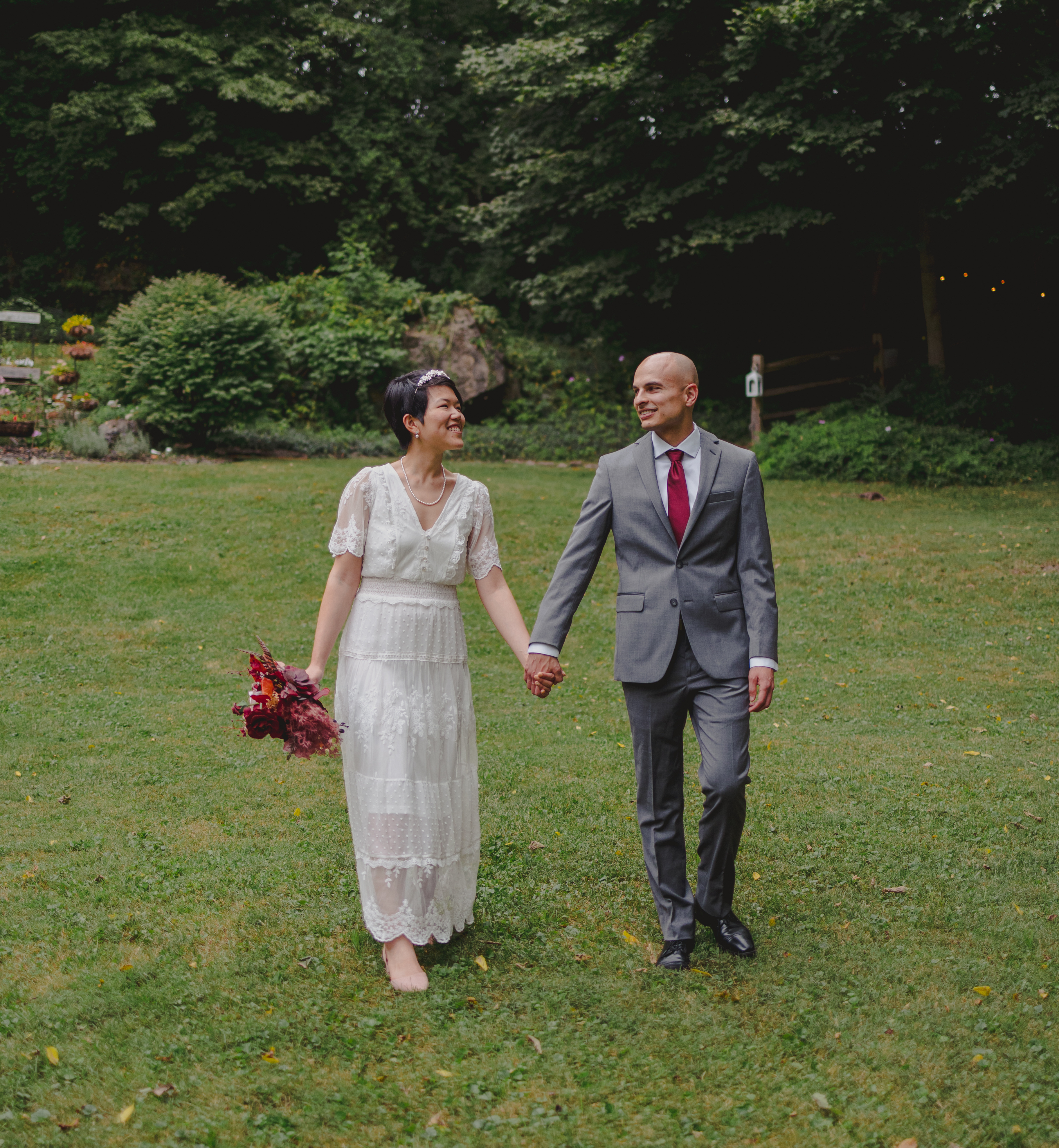 A wedding couple walking through a field.